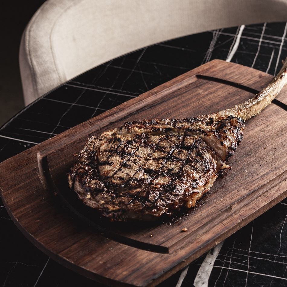 Highly marbled Tomahawk ribeye, mustard-marinated and served bone-in, offering a rich, shareable steak experience.