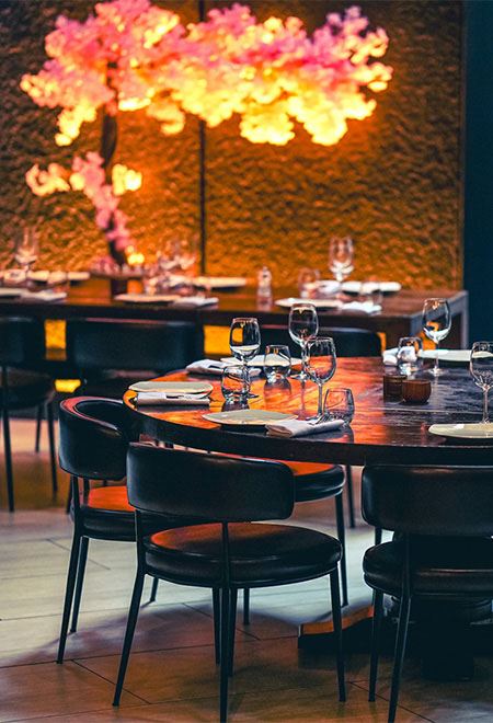 Beautifully set round dining table at Nusr-Et New York Midtown, highlighted by ambient lighting and modern decor for an upscale dining experience.