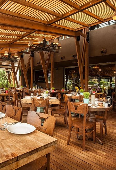 Nusr-Et Ankara features a charming rustic outdoor dining area with wooden beams and furniture, offering a relaxing gourmet experience.