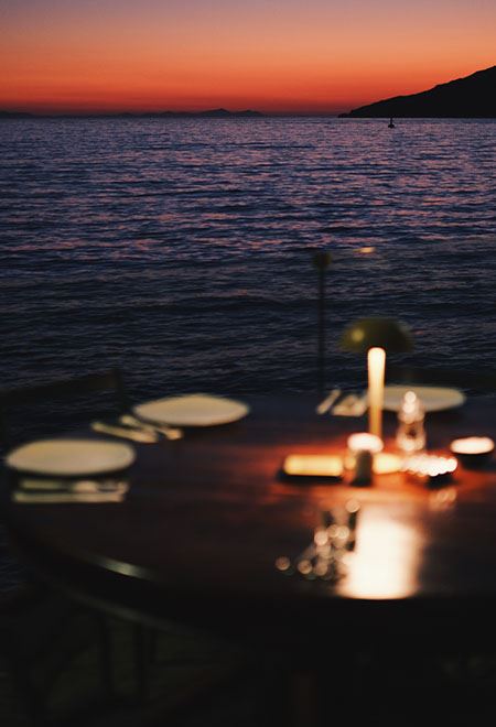 Candle-lit dinner table at Nusr-Et Yalıkavak, with a stunning sunset view over the Aegean Sea, offering an intimate and luxurious dining experience.