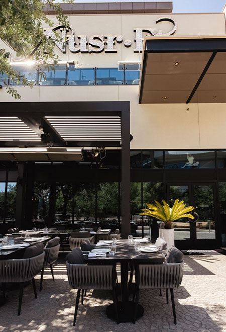 Luxurious dining area at Nusr-Et Las Vegas featuring the iconic 'No Salt No Life' neon sign, modern decor, and an open kitchen.