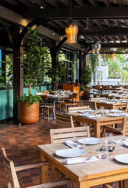 Beautiful outdoor dining area at Nusr-Et Miami, featuring wooden tables and lush greenery, offering a relaxed and luxurious dining experience.