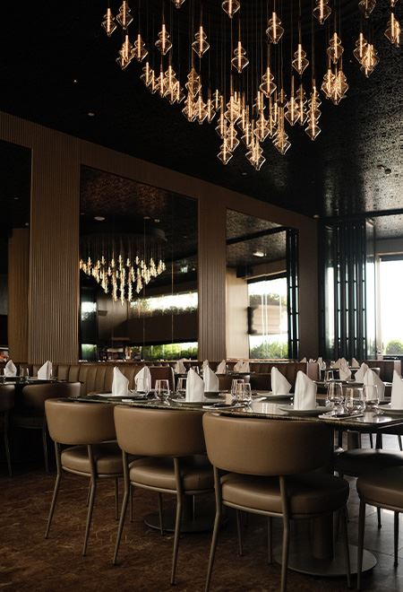 Elegant dining space at Nusr-Et Dubai, located within Dubai Four Seasons Hotel, featuring modern chandeliers and a luxurious setting for an upscale steakhouse experience.