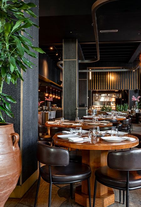 Elegant interior of Nusr-Et Miami with round wooden tables and modern decor, creating a sophisticated steakhouse ambiance.