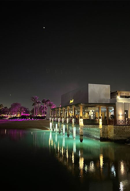 Nusr-Et Doha's stunning waterfront view at night, with the restaurant illuminated against the serene waters of Doha Bay.